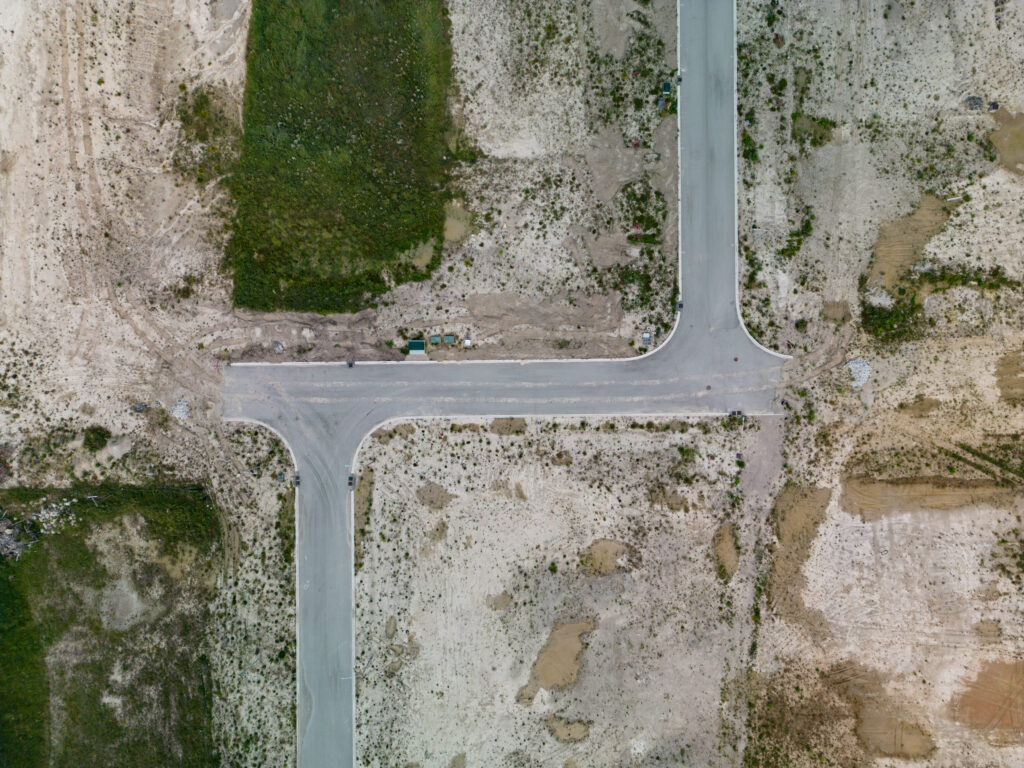 A decorative drone photograph of a construction site for a suburb with an unfinished road.